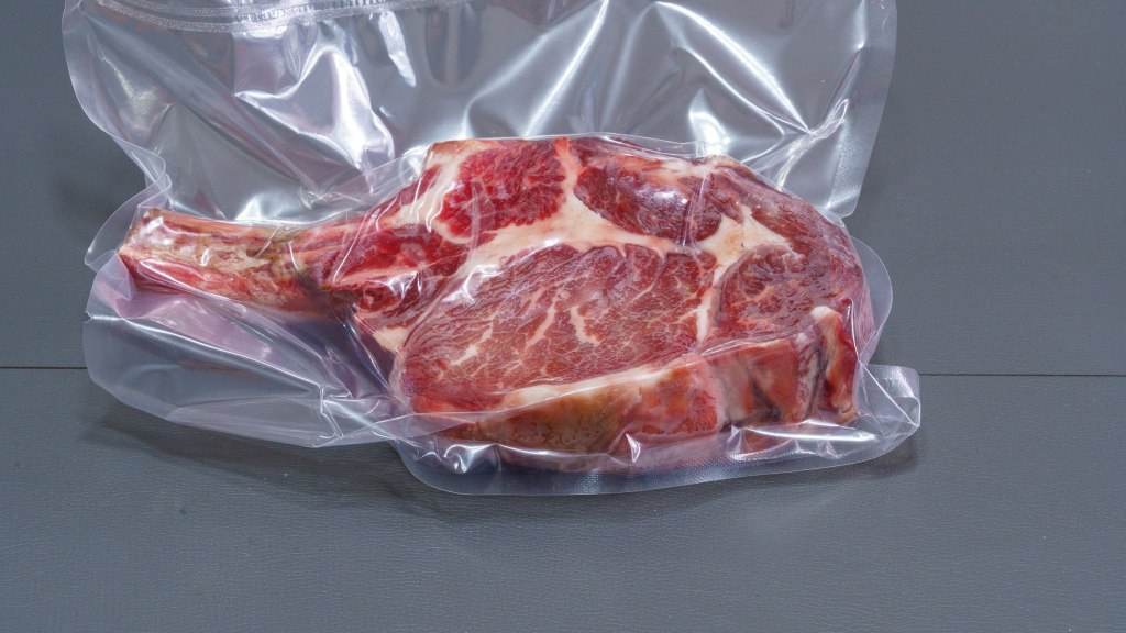 Photograph of dry brined bone-in ribeye steak in a vacuum bag.