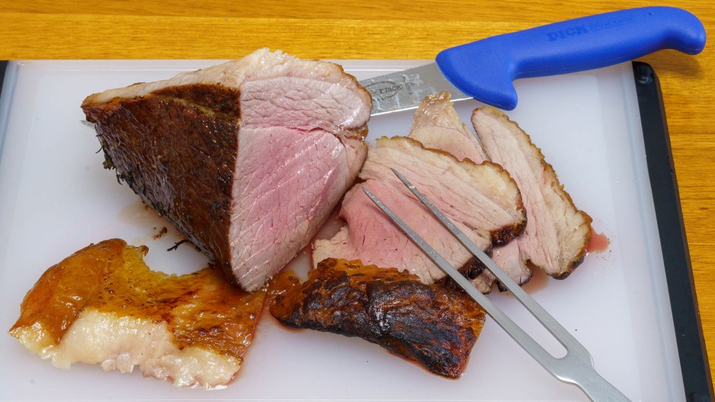 A photograph of the cooked beef on a cutting board with slices of meat and fat. The butchers knife and carving fork are included.