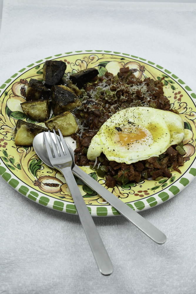 Slowly cooked corned beef hash with fried potato and an egg fried in butter