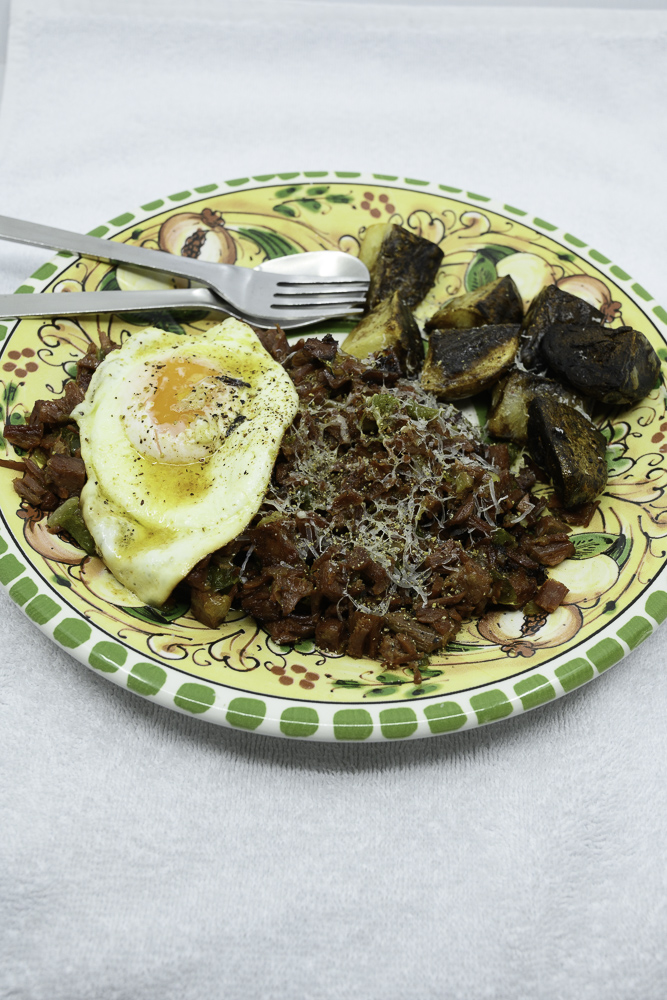 Slowly cooked corned beef hash with fried potato and an egg fried in butter