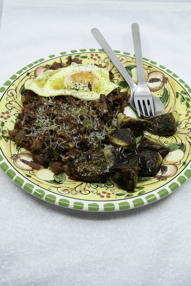 Slowly cooked corned beef hash with fried potato and an egg fried in butter