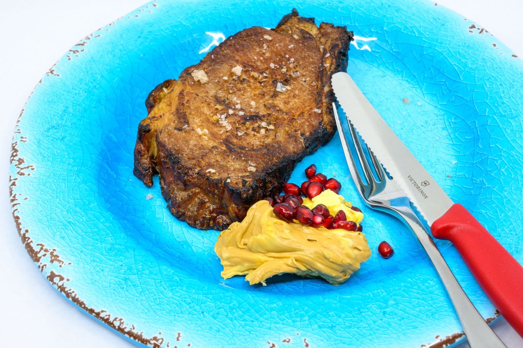 Leftover standing rib roast. I carved it into slices and vacuum-bagged each slice so I could reheat a single slice in a water bath when I wanted to eat a steak. I finished off the steak on a hot barbecue cast-iron flat-top. Served with whipped Vegemite butter and pomegranate arils.