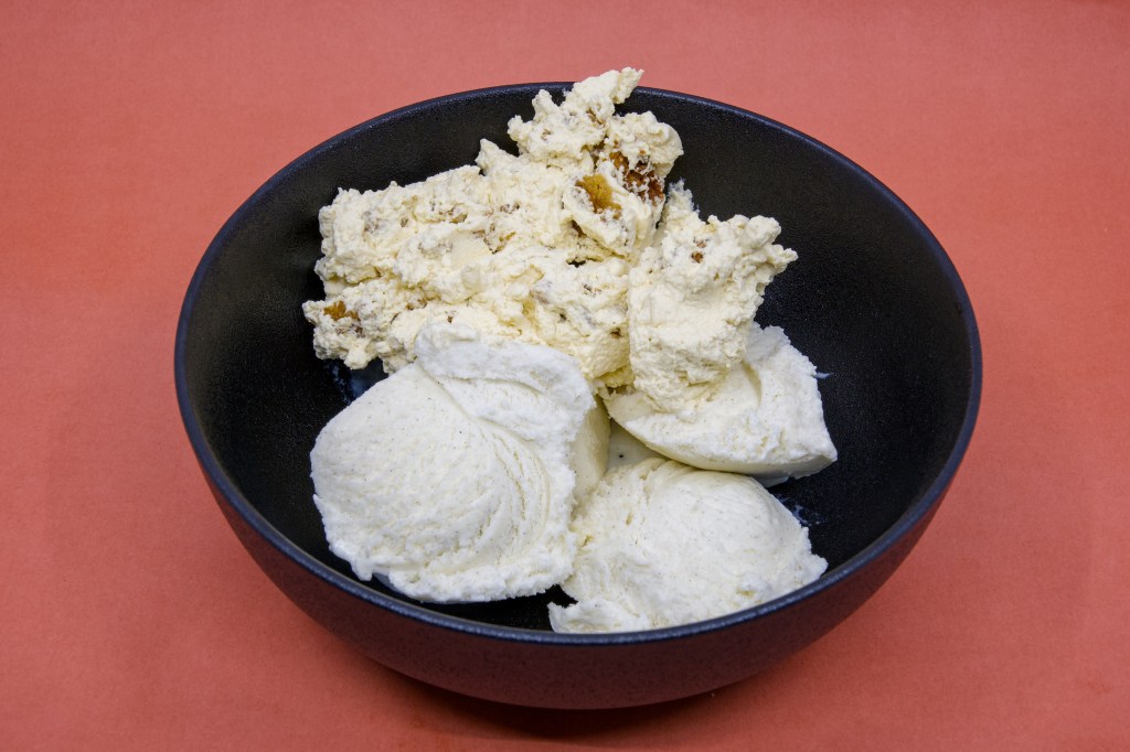 A photograph of Anzac Biscuit Dessert made with a Perryman's Anzac biscuit, freshly whipped Fleurieu Peninsula pure pouring cream, and Golden North vanilla ice cream in a black bowl