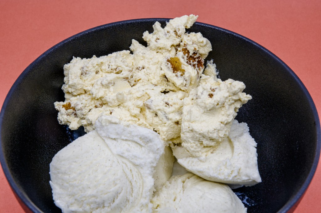 A photograph of Anzac Biscuit Dessert made with a Perryman's Anzac biscuit, freshly whipped Fleurieu Peninsula pure pouring cream, and Golden North vanilla ice cream in a black bowl