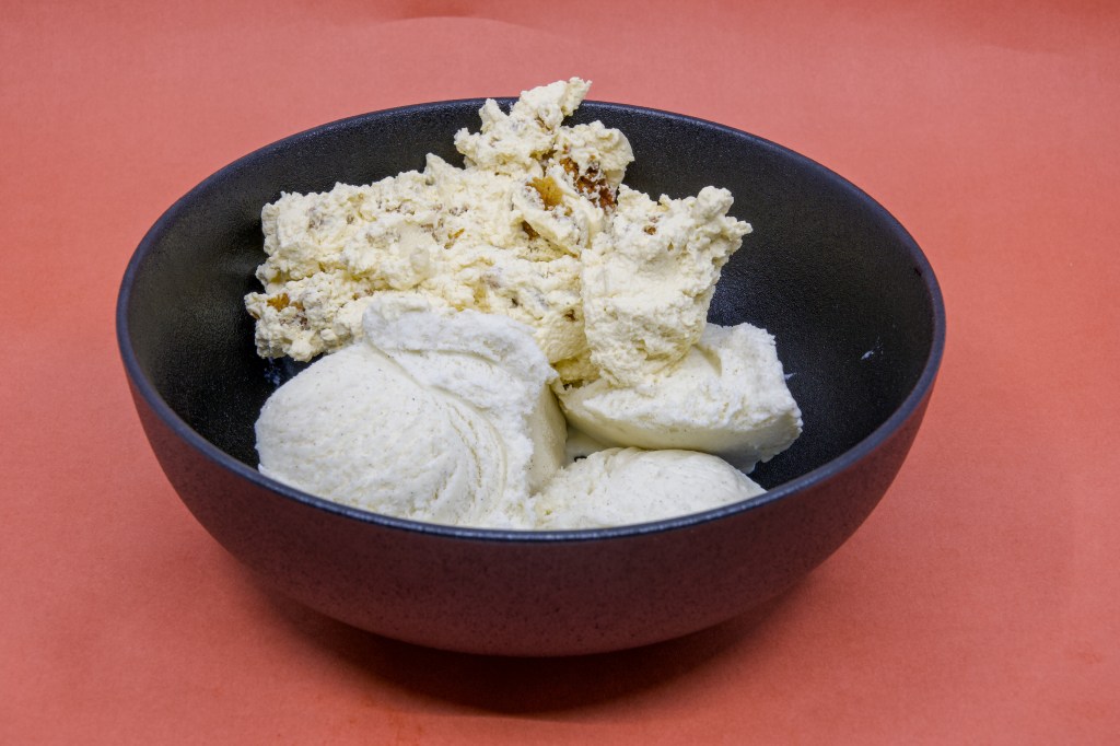 A photograph of Anzac Biscuit Dessert made with a Perryman's Anzac biscuit, freshly whipped Fleurieu Peninsula pure pouring cream, and Golden North vanilla ice cream in a black bowl