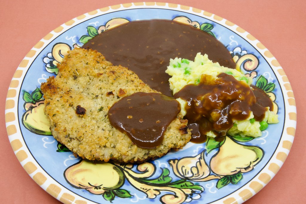 Crumbed pork with peas in potato mash and brown gravy