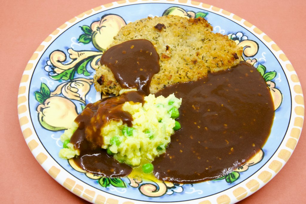 Crumbed pork with peas in potato mash and brown gravy