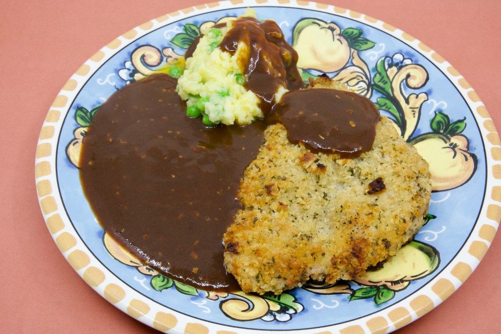 Crumbed pork with peas in potato mash and brown gravy