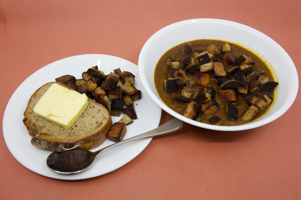 Pumpkin soup with Spam, rye sourdough croutons, and slice of rye sourdough with cultured butter