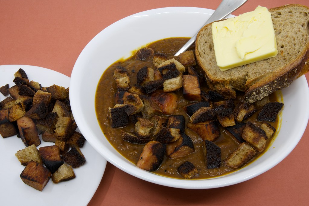 Pumpkin soup with Spam, rye sourdough croutons, and slice of rye sourdough with cultured butter