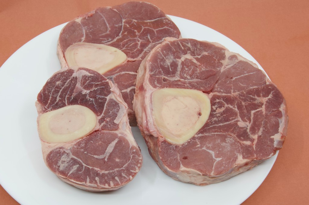 A photograph of three pieces of raw beef shank which have been dried and are ready for searing.