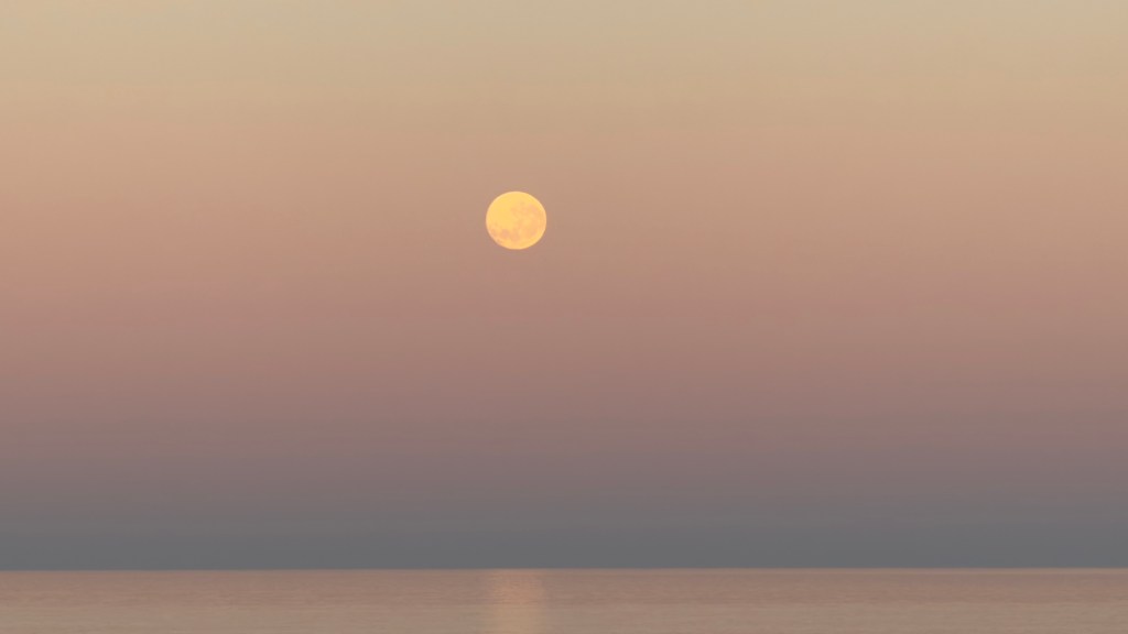 This morning, a photograph captures the full moon setting over Henley Beach in the Indian Ocean.