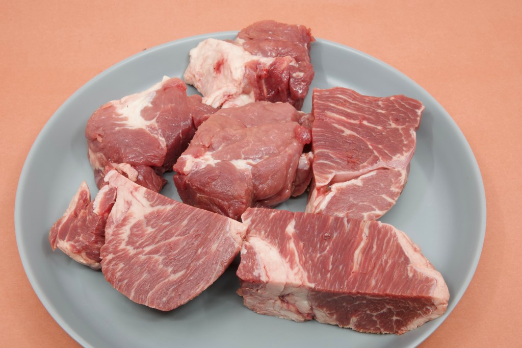 Photograph of a grey plastic plate with six chunks of raw beef chuck