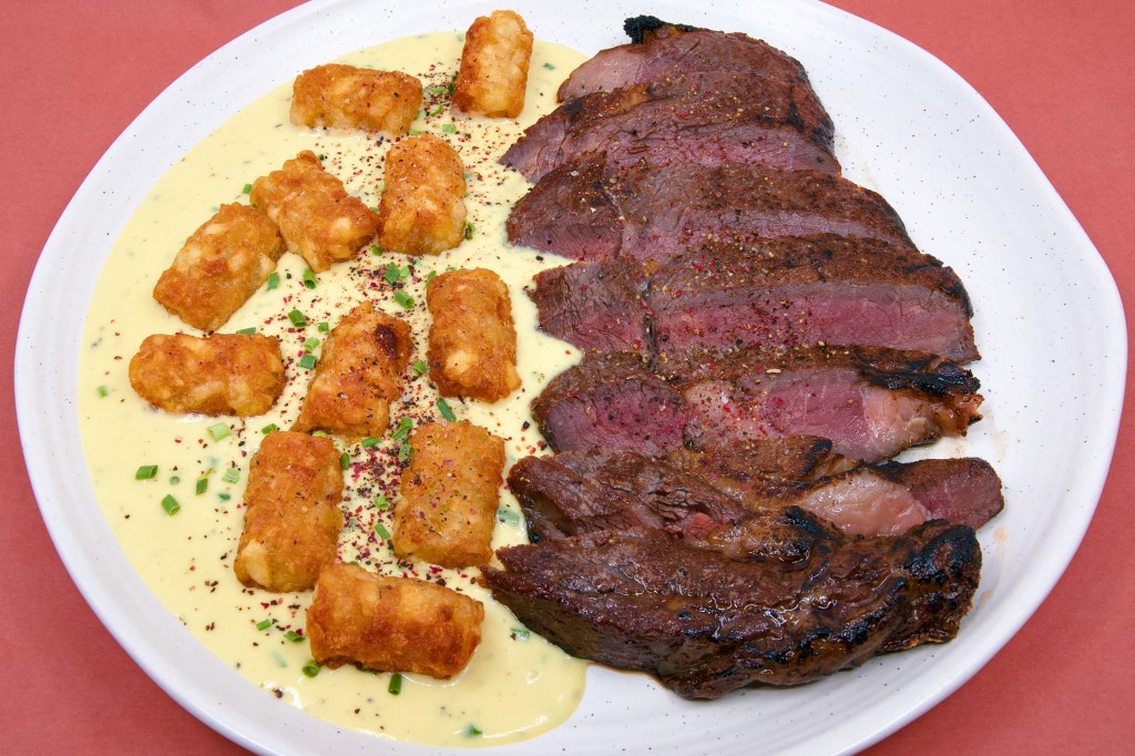 Dry-brined scotch fillet steak cooked sous vide at 57 °C for 1 hour and seared with a gas blow torch, served with crispy beef-fat potato gems on a creamy blue brie cheese sauce, garnished with cracked peppercorns and fresh chives.