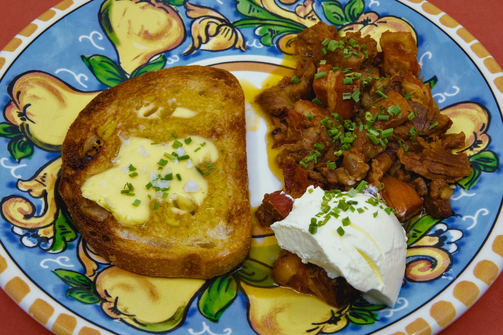 Plate of mixed mammal stew with toasted rye sourdough bread spread with two layers of butter, served alongside a dollop of Greek-style yoghurt and sprinkled with chives.